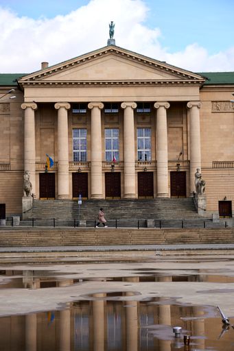 A vertical shot of a rain puddle in front of the Grand Theater building in Poznan, Poland
