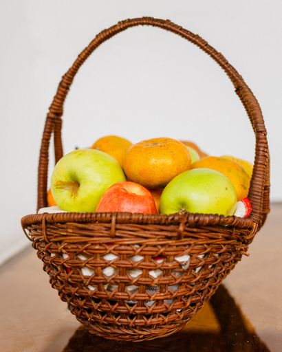 A close up shot of a juicy fruit basket containing apples and tangerines