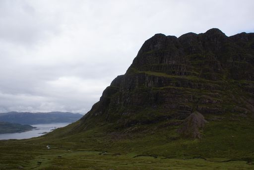 A beautiful view of rocky mnountain covered with moss under a cloudy sky in Scotland