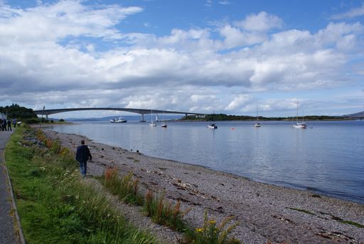 A scenic view of sandy shore and mountain landscape in Scotland under a cloudy sky
