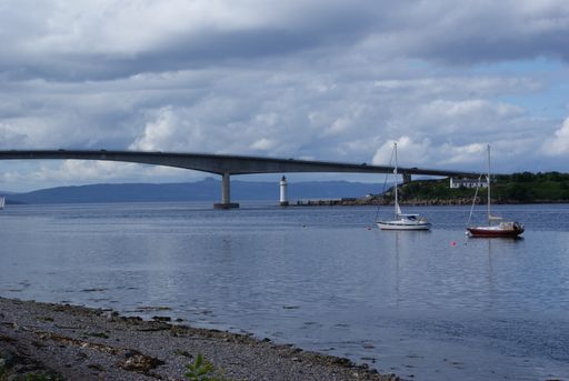 A beautiful view of boats moored on the sea near a bridge in Scotland