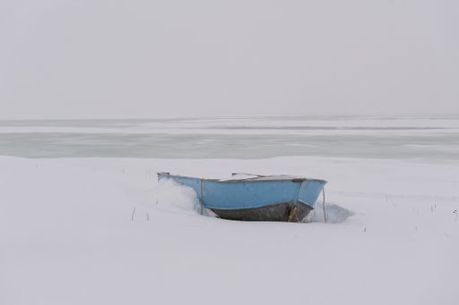 A small fishing boat partially covered in snow along Alaska's coast mid winter