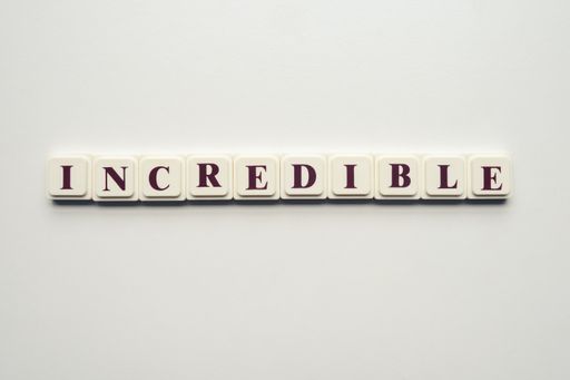 A closeup of scrabble tiles with letters spelling the message "Incredible" on a white background