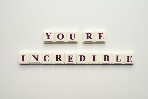 A closeup of scrabble tiles with letters spelling the message "You're Incredible" on a white background