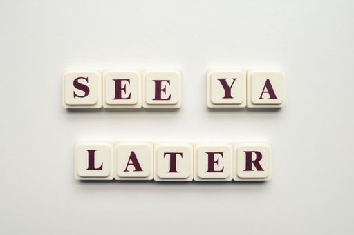 A closeup of scrabble tiles with letters spelling the message "See Ya Later" on a white background