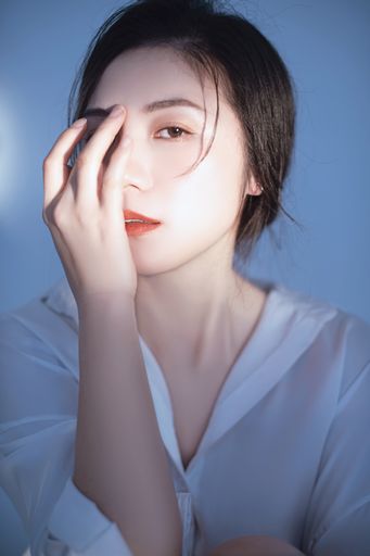 A closeup portrait of a beautiful Asian woman covering her face with her hand
