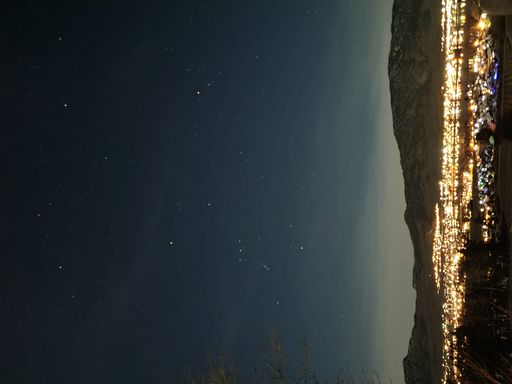 A beautiful night view of lights in front of mountain in desert under starry sky