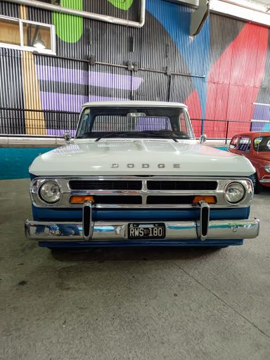 White and sky blue old Chrysler Dodge D 200 pickup truck late 1960s parked in a warehouse yard. Front view. Classic car show. Copyspace