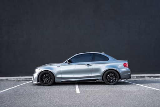 A side profile of a silver BMW 1 series parked in a parking lot