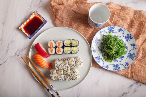 A top view of Japanese sushi nigiri and rolls, wakame seaweed salad, soy sauce and chopsticks on a table