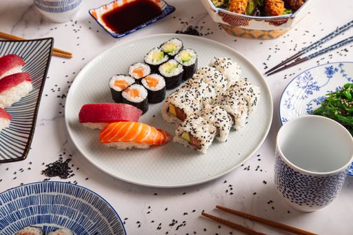 Traditional Japanese sushi nigiri and rolls mix served on a white plate at a restaurant