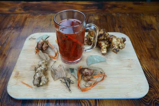 A high angle shot of a cup of tea and some ginger on a wooden surface on a table