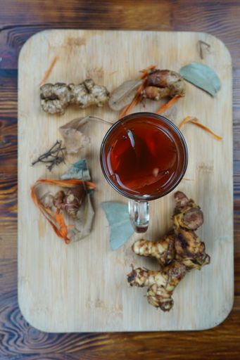 A vertical high angle shot of a cup of tea and some ginger on a wooden surface on a table