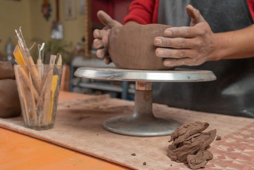 A closeup shot of Hispanic potter hands making and molding a clay vessel in his workshop