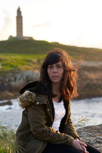A vertical shot of a brunette Caucasian woman behind the river and the tower