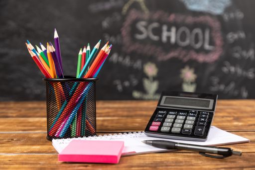 A closeup shot of colored pencils with calculator and chalkboard