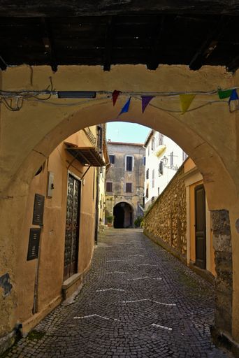A vertical shot of an arched narrow cobblestone alley among houses in Fiuggi, Lazio, Italy