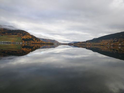 A beautiful view of a lake surrounded by rocky mountains under a cloudy sky