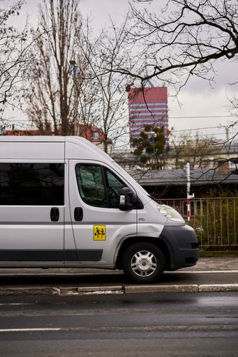 A parked school transport van on a sidewalk in the city center on a rainy day