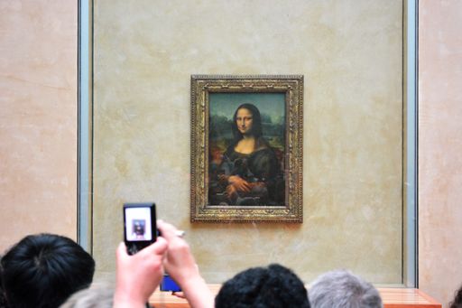 A photo someone taking a photo of the Mona Lisa in a museum in Paris, France