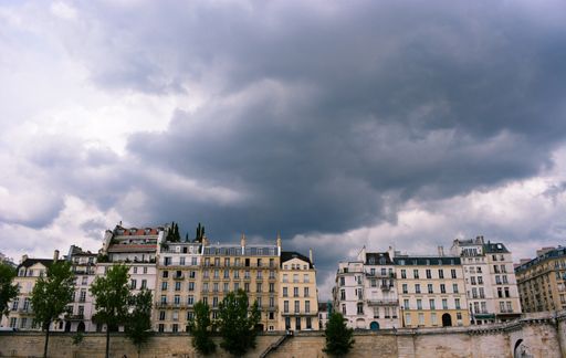 A beautiful low angle shot of the Quay of Orleans building in Paris France against a gray cloudy sky