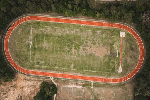 An aerial shot of a green football field and red running tracks