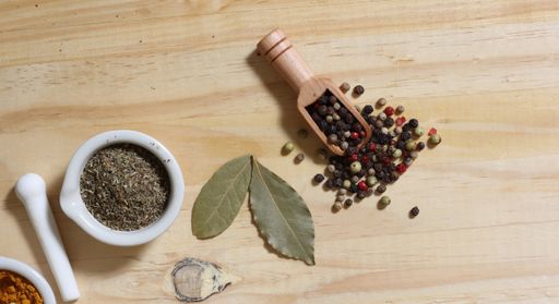A top view of a Mortar and Pestle With Herbs and Peppercorns on Wooden table