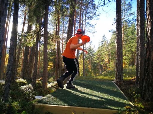 A man wearing sporty clothes, playing frisbee in a forest