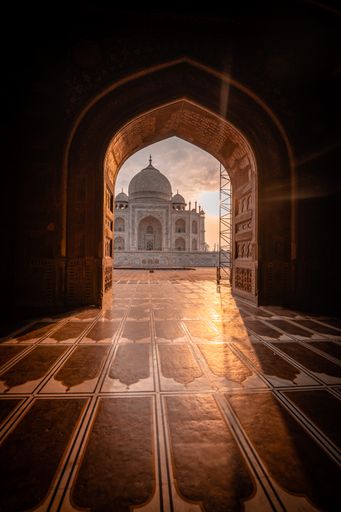 A low angle of a scenic view of the Taj Mahal Mausoleum at sunset through the archway of the mosque, Agra, India