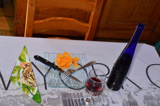 A top view of a meal consisting of potato chips and a bottle of wine in a white tablecloth