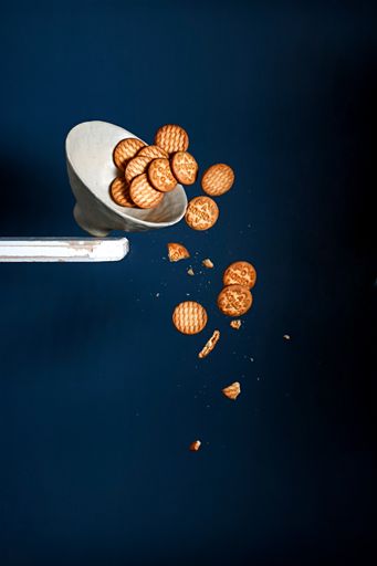 the Studio shot of Cookies falling from a bowl isolated  on a blue background