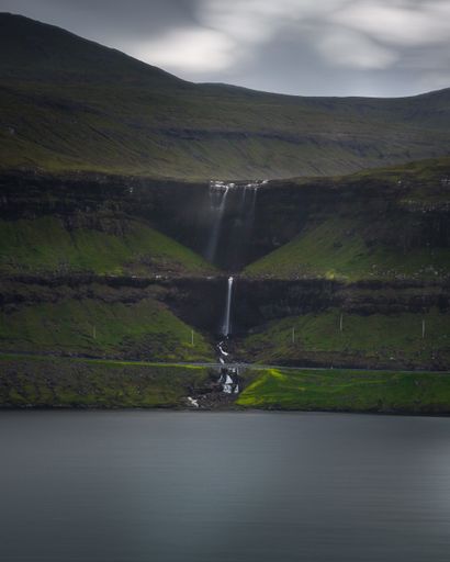 A vertical  shot of the Fossa waterfall in Faroe Island on a gloomy day