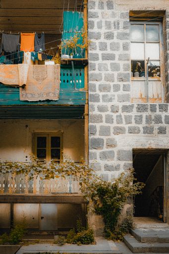A vertical shot of a traditional Armenian building's facade with balconies, hanged clothes and carpets