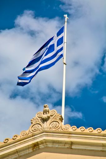 A vertical shot of the Flag of Greece on top of the Greek parliament building