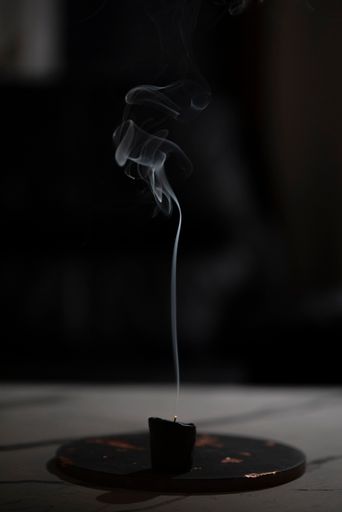 A vertical shot of the smoke of a candle in a dark room