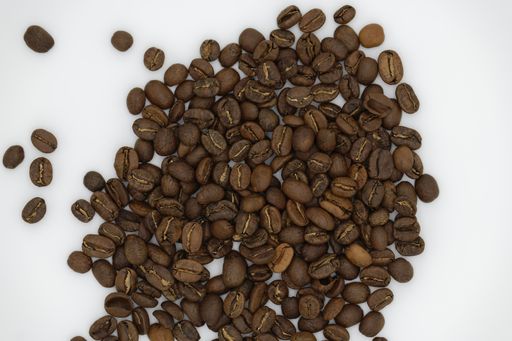 A high angle shot of coffee beans on a white surface