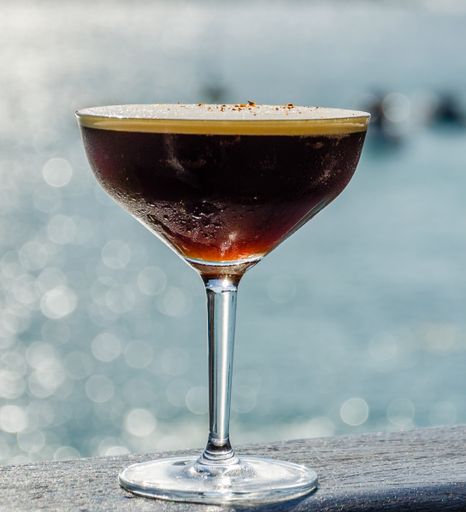 A selective focus shot of an alcoholic cocktail with a background of the sea