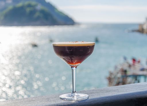 A selective focus shot of an alcoholic cocktail with a background of the sea