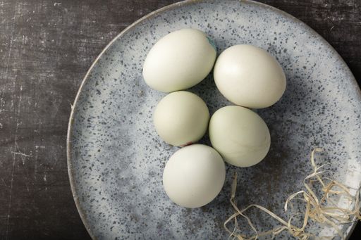 A high angle shot of eggs in a plate on a dark metallic surface
