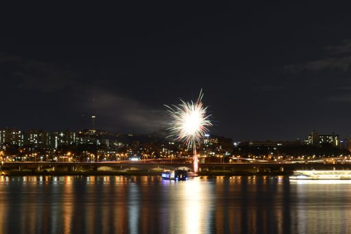 A beautiful scenery of fireworks over an illuminated cityscape at Han-River in Seoul, South Korea