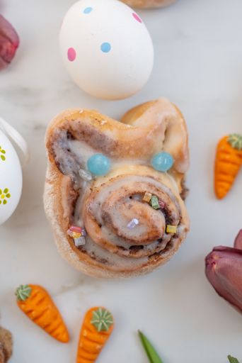 A vertical closeup shot of cinnamon buns, eggs, and other Easter decorations on a table