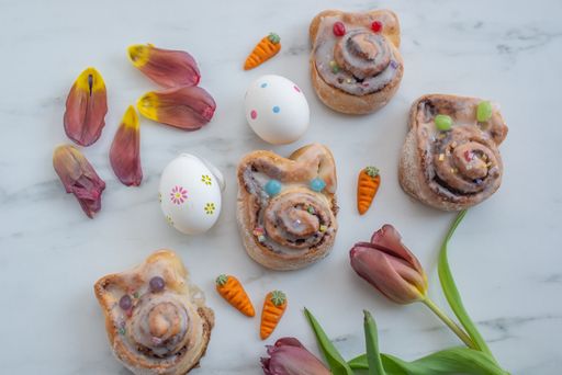 A closeup shot of cinnamon buns, eggs, and other Easter decorations on a table