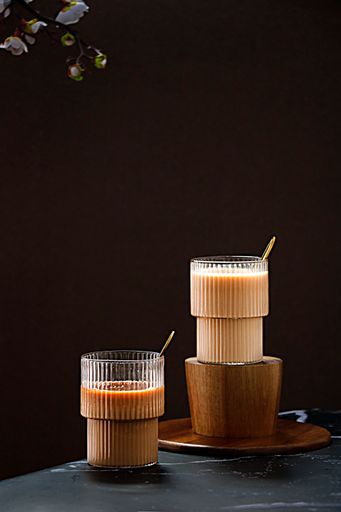 A vertical shot of two cups of iced coffee on the black tabletop