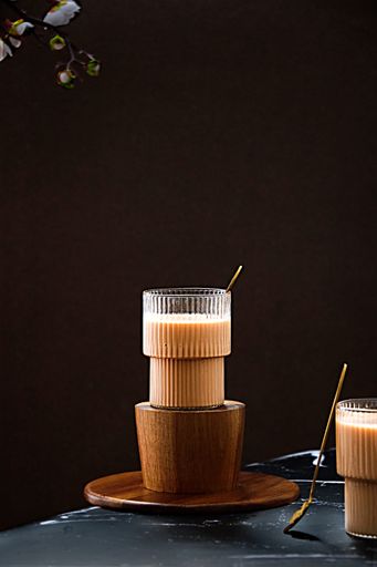 A vertical shot of two cups of iced coffee on the black tabletop