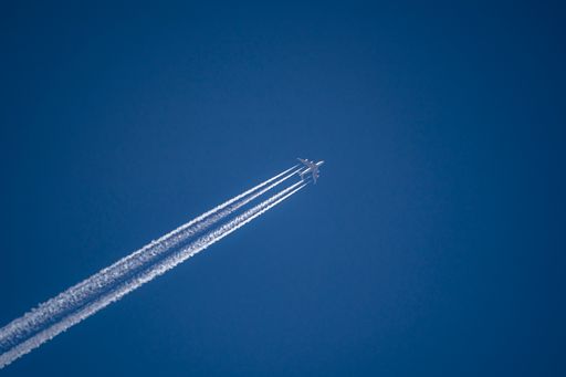 A photo of a plane with condensation tracks