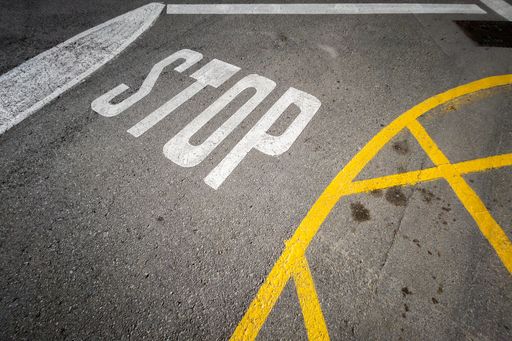 A vertical shot of a road with stop road marking in a city