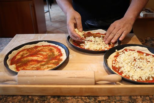 A closeup of a person's hand cooking Italian pizza on the kitchen table