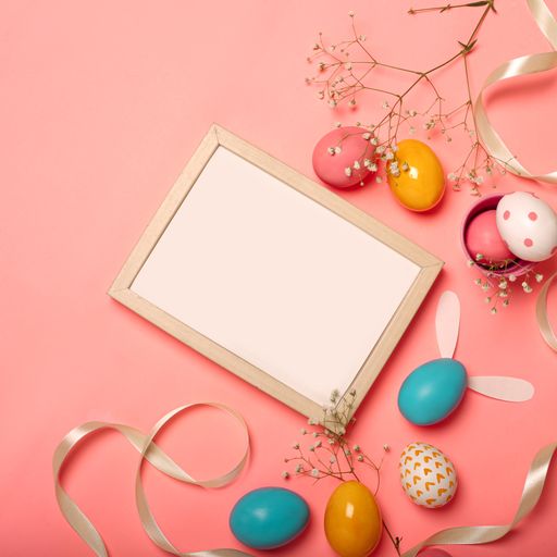 A top view of colorful Easter eggs and a blank frame for copy space on a pink background