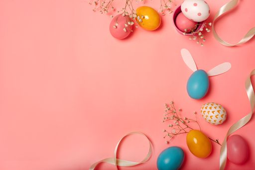 A top view of colorful Easter eggs and decorations on a pink background