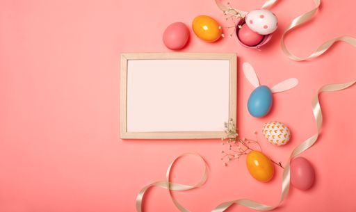 A top view of colorful Easter eggs and a blank frame for copy space on a blue background
